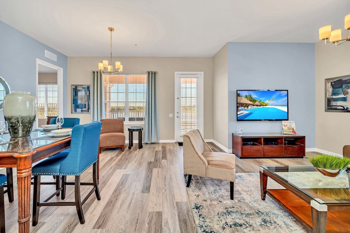 A modern living room with a dining area, a television, and a view of a pool.