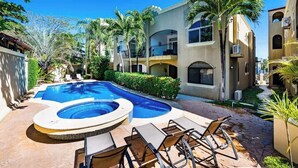 A swimming pool with lounge chairs, surrounded by multi-story buildings with balconies and air conditioning units. - Guapinol 3☀Pool and AC♆ close to Beach ⛱ and Restaurant (Langosta)