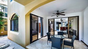 A modern patio with a glass door leading to a bedroom, a dining area with a table and chairs, and a ceiling fan. - Guapinol 3☀Pool and AC♆ close to Beach ⛱ and Restaurant (Langosta)