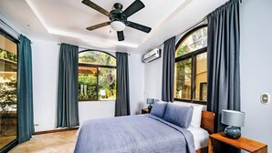 A modern bedroom with a large bed, a ceiling fan, and two windows with curtains. - Guapinol 3☀Pool and AC♆ close to Beach ⛱ and Restaurant (Langosta)