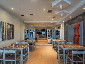 A restaurant with booths and tables, a counter, and artwork on the walls. - Dias Hotel & Spa (Dio-Olympos)