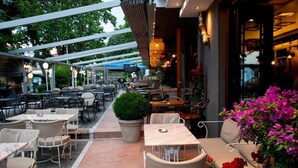 An outdoor cafe with tables and chairs, a pathway, and potted plants. - Dias Hotel & Spa (Dio-Olympos)