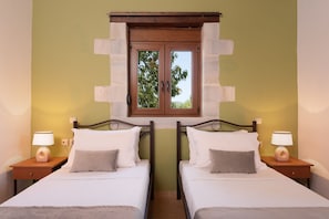 A hotel room with two beds, a window with a view of trees, and bedside lamps.
