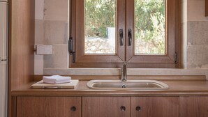 Une salle de bain avec un meuble-lavabo en bois, un évier et une fenêtre donnant sur un paysage verdoyant.