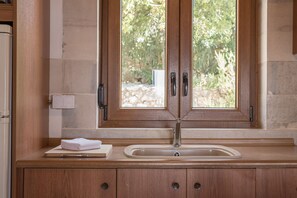 A kitchen with a wooden countertop, a sink, and a window with a view of greenery.
