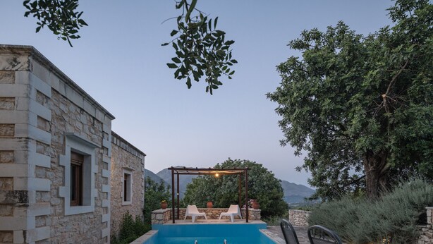 Un bâtiment en pierre doté d’une piscine, d’un espace extérieur aménagé et d’une pergola.