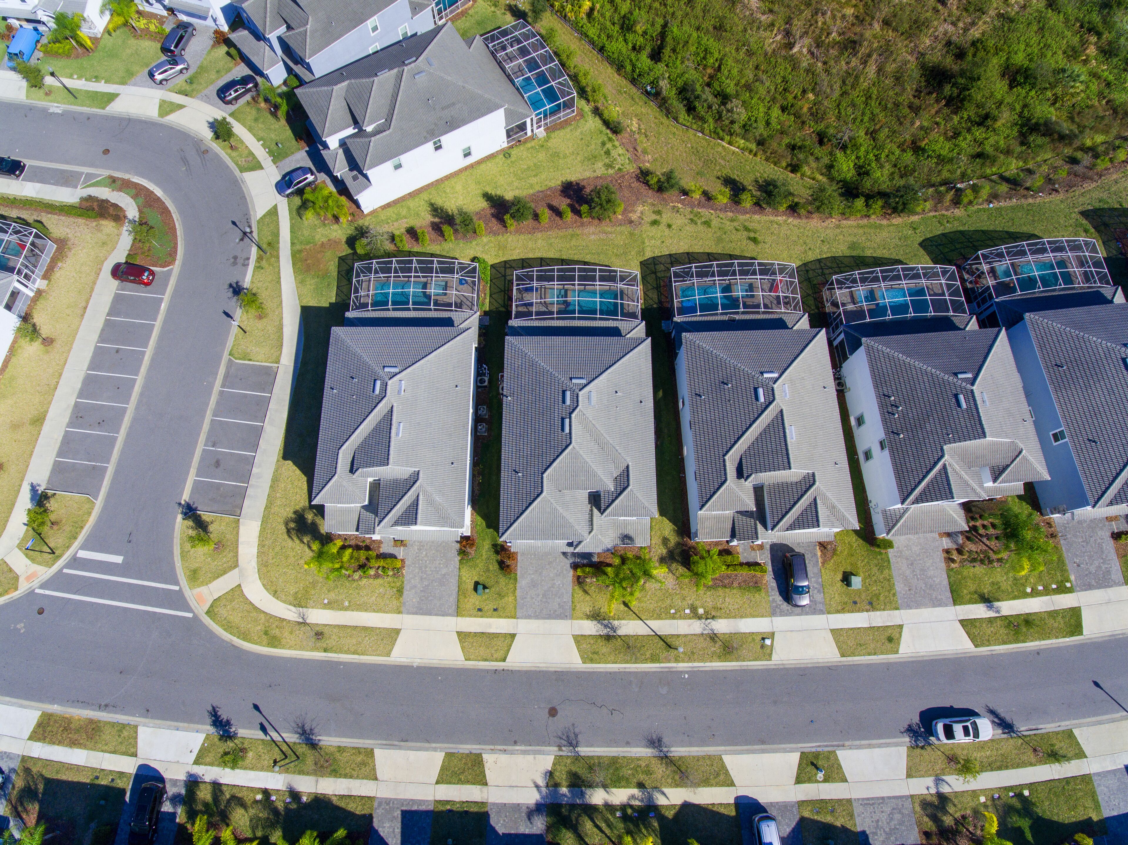 A residential area with multiple houses, a parking lot, and a curved road.