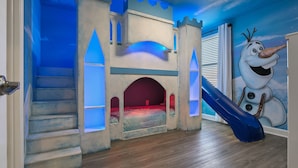 A child's playroom with a castle-themed bed, a slide, and a snowman mural. - 8BR Villa,Outstanding Game Room,Resort - by Blue Sky Villas (Championsgate)
