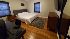 A bedroom with a bed, desk, chair, computer, and TV.