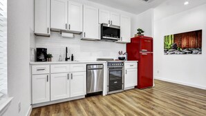 A modern kitchen with white cabinets, stainless steel appliances, and a red refrigerator. - Pitch Perfect! Minutes from Canyon Lake! (Canyon Lake)
