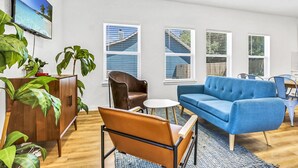 A modern living room with a blue sofa, a brown leather chair, and a wooden cabinet with plants. - Pitch Perfect! Minutes from Canyon Lake! (Canyon Lake)
