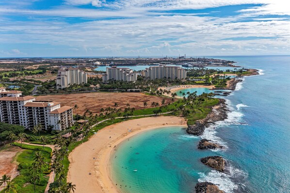Un complejo turístico frente al mar con propiedades en la playa, una playa de arena y vistas claras del océano.