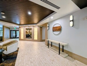 A hotel lobby with a herringbone floor pattern, a reception desk, a massage area, and a wall-mounted clock. - Renovated w/Fireplace, Walk to Gondola, Hot Tubs (Keystone)