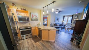 A kitchen with a refrigerator, stove, microwave, and wooden cabinets. There is a dining area with a table and chairs. - Renovated Unit W/Fireplace, Walk to Restaurants. (Keystone)