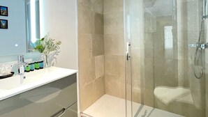 Une salle de bain moderne avec une douche à parois de verre, un lavabo blanc avec un miroir et des toilettes.