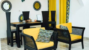 A dining area with black chairs and yellow cushions, a table with a laptop, and decorative mirrors on the wall. - Spacious 5 BR Villa with amazing views Bar&Pool | family & large groups | Wi-Fi (Accra)