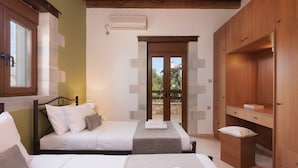 A bedroom with two beds, a wooden wardrobe, and a view through a glass door. - Koules Estate-Helianthus, with Pool & BBQ,an Agricultural barn for Nature lovers (Rethymno)