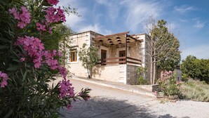 A stone building with a balcony, surrounded by greenery and flowers. - Koules Estate-Helianthus, with Pool & BBQ,an Agricultural barn for Nature lovers (Rethymno)