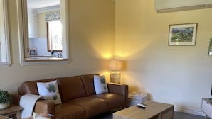 Sala de estar com sofá de couro marrom, mesa de centro de madeira e uma luminária.