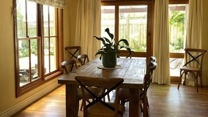 Uma sala de jantar com uma mesa de madeira, cadeiras e um vaso com planta.