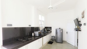 Een moderne keuken met witte kastjes, een zwart aanrecht, een roestvrijstalen koelkast en een magnetron.