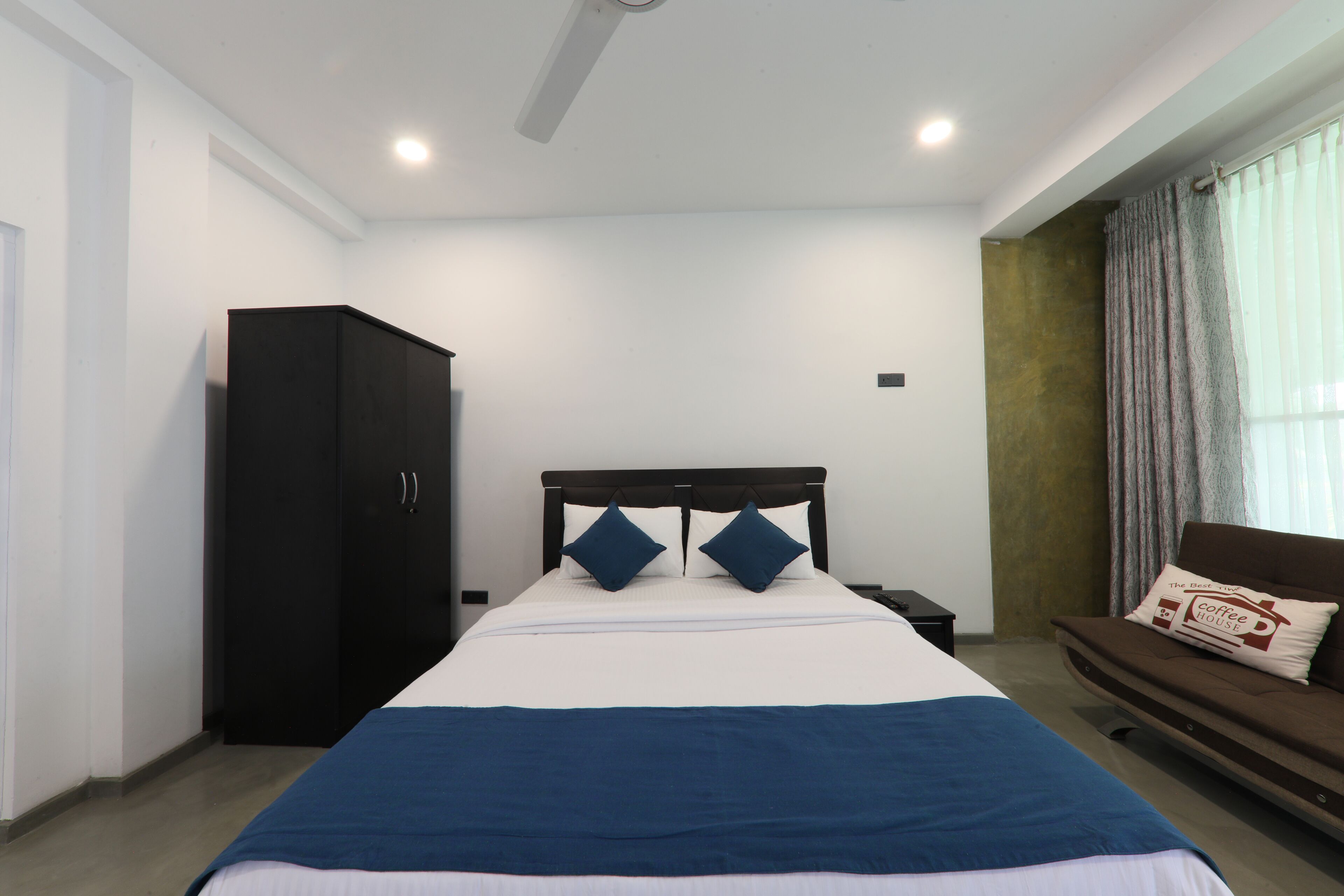 A bedroom with a bed, a wardrobe, a nightstand, and a sofa.