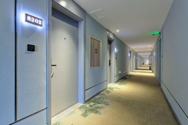 A hotel corridor with doors marked with room numbers, a carpeted floor, and a long, straight layout. - Homeinn Pebble Hotel (Danyang Zhongshan Road Glasses City) (Danyang)