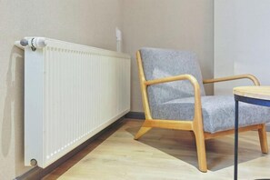 A room with a radiator, a grey upholstered chair, and a small round table. - Homeinn Pebble Hotel (Danyang Zhongshan Road Glasses City) (Danyang)