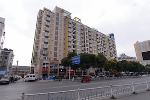 Un edificio de varios pisos con planta comercial, zona de estacionamiento y una calle delante.