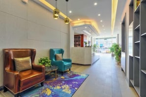 A hotel lobby with leather armchairs, a reception desk, and a colorful rug.