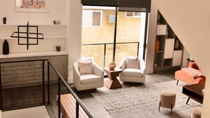 Een ruime woonkamer met een trap, een balkon en een eethoek.