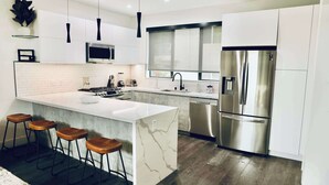 Een moderne keuken met een centraal eiland, roestvrijstalen apparatuur en een paar barstoelen.