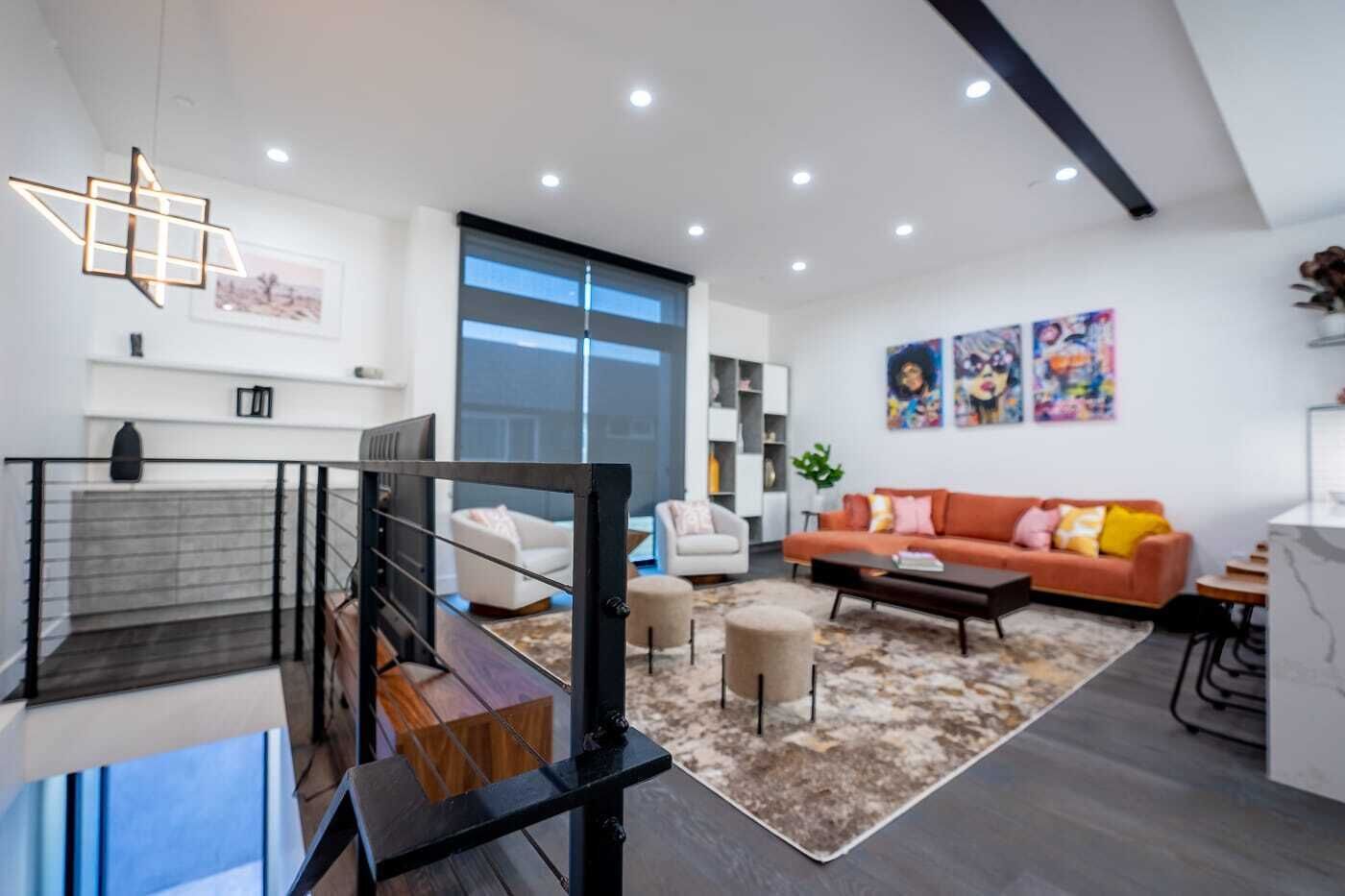 Una sala moderna con una escalera, un conjunto de sofás y una mesa de centro.