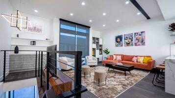 Una sala moderna con una escalera, un conjunto de sofás y una mesa de centro.