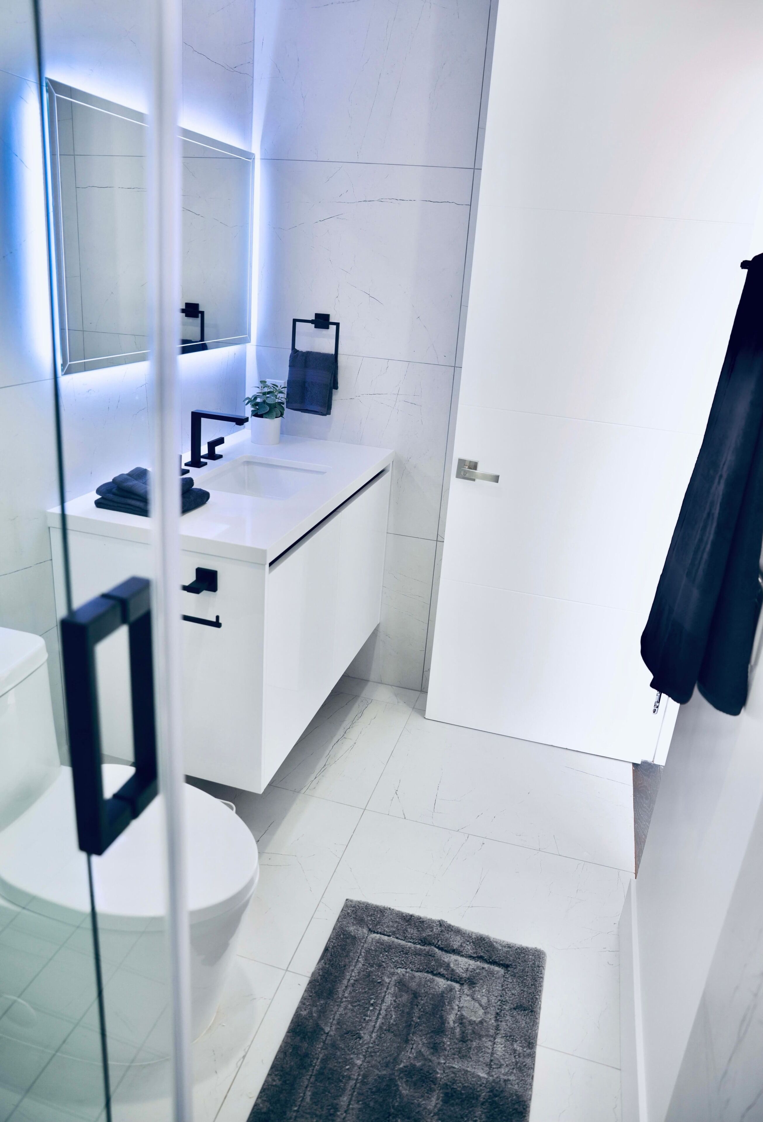 A modern bathroom with a white sink, mirror, and toilet.