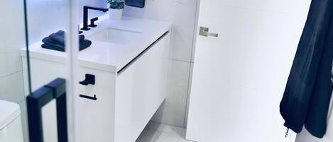 A modern bathroom with a white sink, mirror, and toilet.
