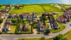 An aerial view of a coastal residential area with houses, roads, and a body of water. - Spacious 12-Bedroom Coastal Retreat Private Annex (Mundesley)