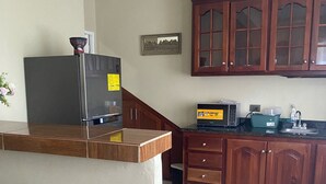 Uma cozinha com armários de madeira, geladeira, micro-ondas e pia.