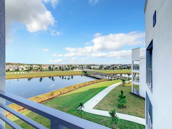 A residential area with a pond, a bridge, and modern houses.