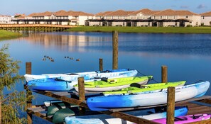 A calm lake with several kayaks docked at a wooden pier.