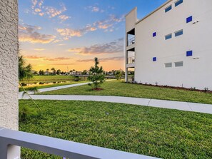 A modern building with a flat roof and multiple windows, surrounded by a well-maintained lawn and a small pond.