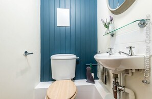 Un baño con una puerta azul, un inodoro blanco, un lavabo y un espejo.