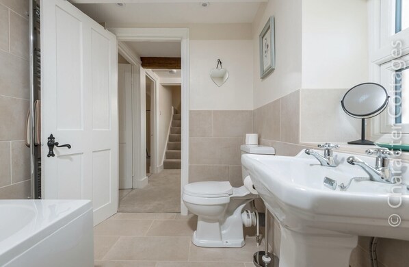 A bathroom with a bathtub, toilet, sink, and a mirror. - Wall Cottage (Burford)