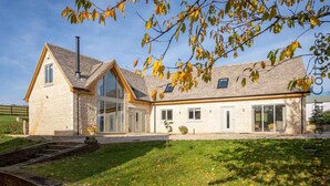 A stone house with a large glass window, a chimney, and a well-maintained lawn. - Hetty's Stables (Cheltenham)