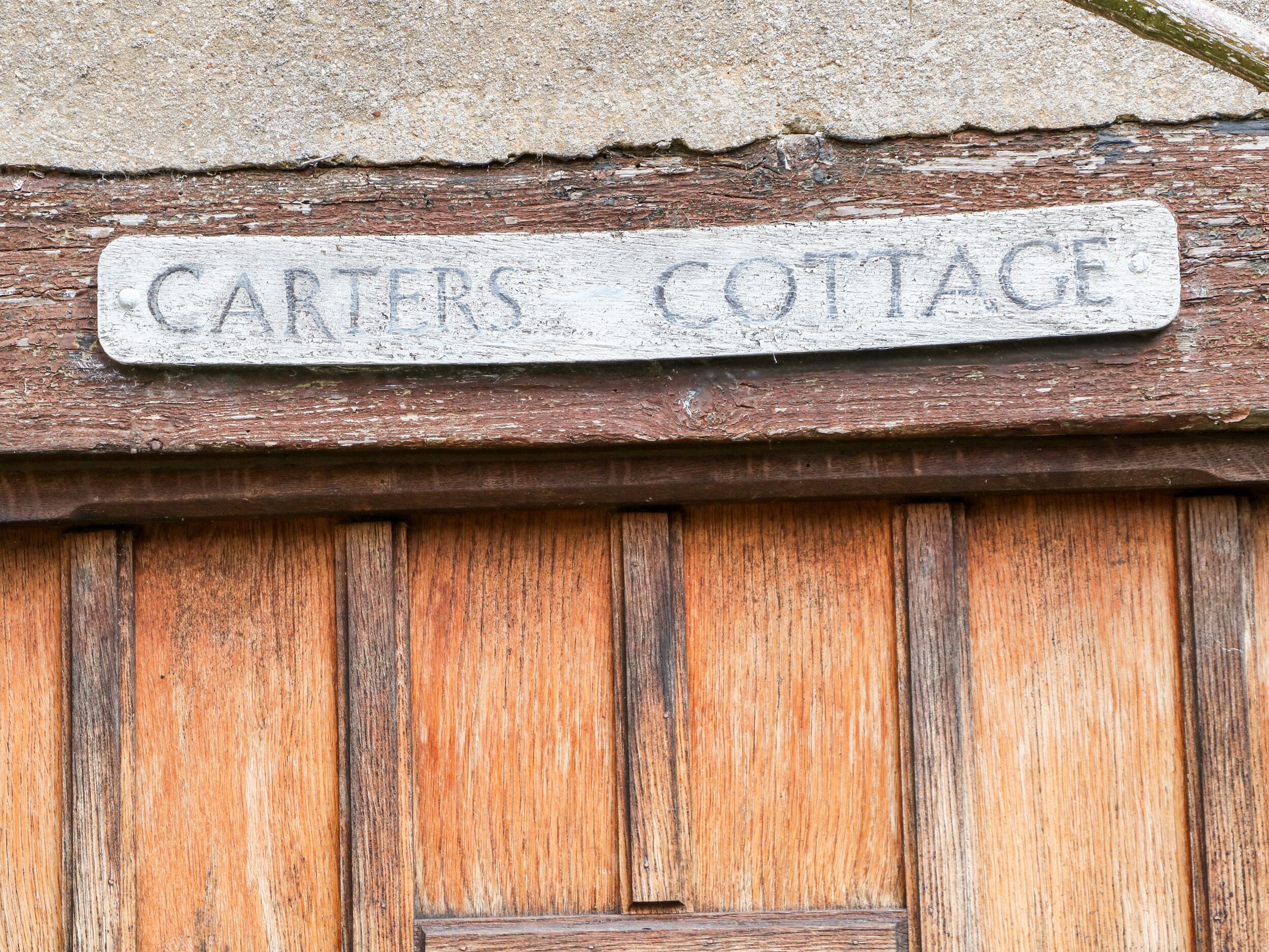 A wooden door with a sign above it that reads "CARTERS COTTAGE".