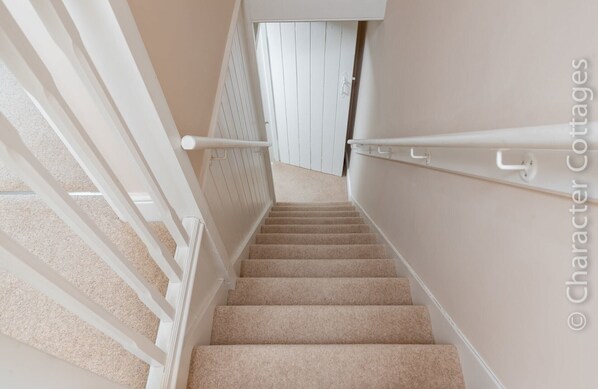 A carpeted staircase with white railings and a beige wall. - Mount View (Broadway)