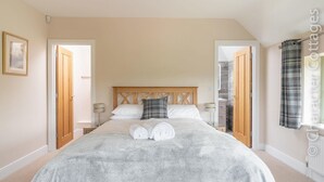 Un dormitorio con una cama grande, dos mesitas de noche, un cabecero de madera y una ventana con cortinas.