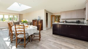 Una cocina moderna con armarios oscuros, encimera de mármol y comedor con mesa dispuesta para cuatro personas.