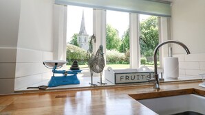 Eine Küche mit einem großen Fenster, einer Waage, einem Obstkorb und einem Spülbecken.