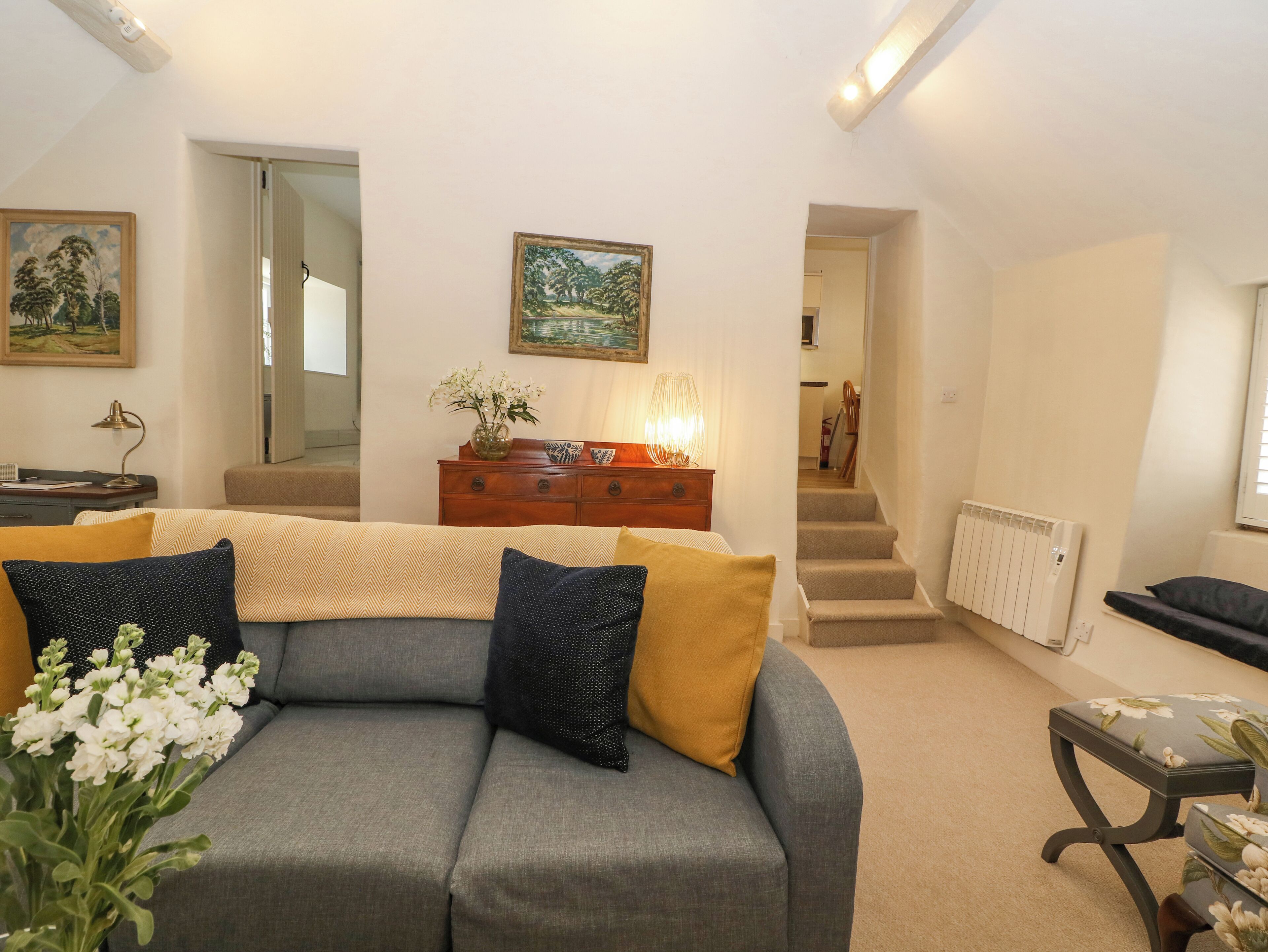 Un salón con un sofá gris, un mueble de madera y un cuadro en la pared.